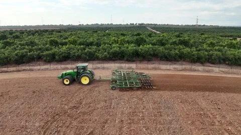 Aerial drone view of a John Deere tractor plowing a large agricultural field Stock Footage 293956942