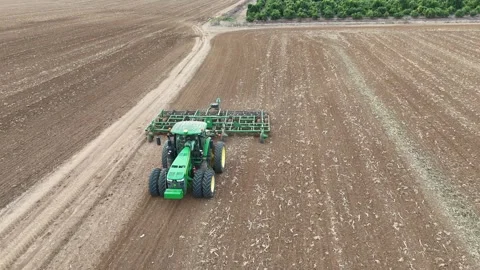 Aerial drone view of a John Deere tractor plowing a large agricultural field Stock Footage 293956945