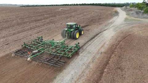 Aerial drone view of a John Deere tractor plowing a large agricultural field Stock Footage 293956954