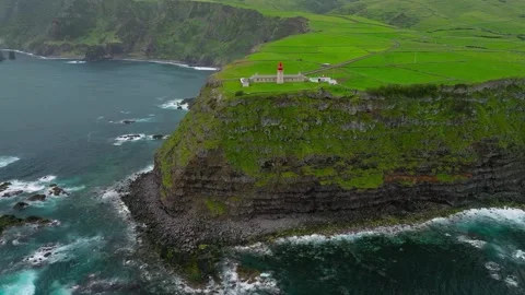 Aerial drone view of lighthouse on lush green coastal cliff Stock Footage 345467194