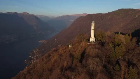 Aerial drone view of a lighthouse over Lake Como skyline with sunset light Stock Footage 169540164