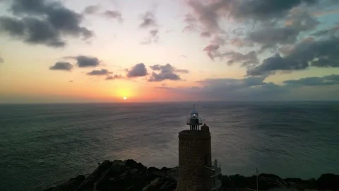 Aerial drone view of lighthouse by sea cliffs at sunset Stock Footage 293064130