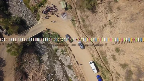 Aerial drone view looking down away from a suspension bridge with people walking 库存影片 198772632