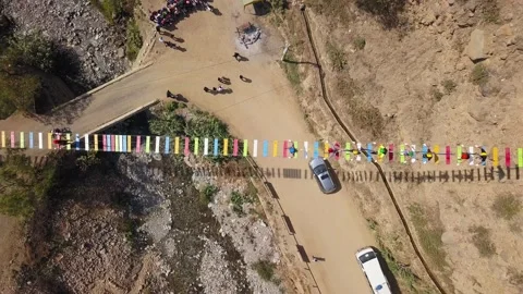 Aerial drone view looking down a suspension bridge with people walking on the co Stock Footage 198795079