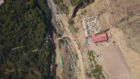 Aerial drone view looking down away from a suspension bridge with people walking Stock Footage 198795621