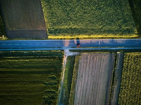 Aerial drone view looking down on a rural road with a car driving along it. On a Stock Photos