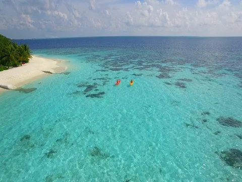 Aerial drone view of a man and woman couple kayaking around a tropical island. Stock Footage