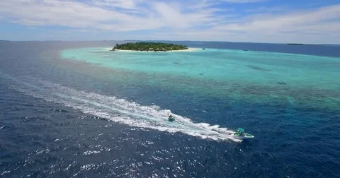 Aerial drone view of a man and woman on an inflatable tube towing behind a boat Stock Footage