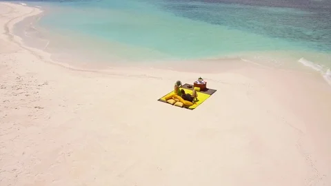 Aerial drone view of a man and woman couple having a picnic meal on a tropical i Stock Footage