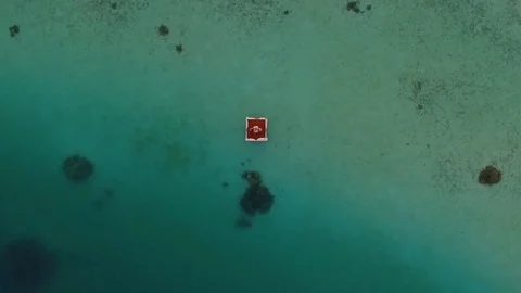 Aerial drone view of a man and woman having dinner on a floating raft boat at su Stock Footage