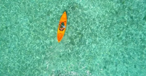 Aerial drone view of a man and woman couple kayaking around a tropical island. Stock Footage