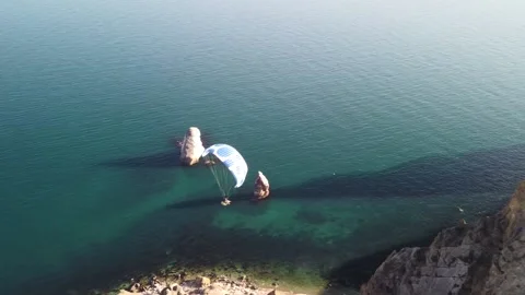 Aerial drone view of a man flying a white and blue paraglider over a hill and Stock Footage 171908465