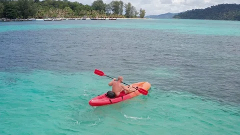 Aerial drone view of man kayaking in crystal clear lagoon sea water during su Stock Footage 108328408