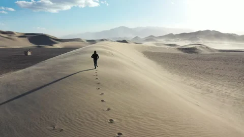 Aerial Drone View of a man running along the top of a sand dune Stock Footage 326723482