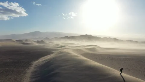 Aerial Drone View of a man walking across the top of a Sand Dune Stock Footage 326721366