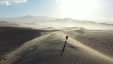 Aerial Drone View of a man walking across the top of a Sand Dune Stockbeeldmateriaal 326721426