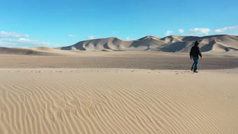 Aerial Drone View of a man walking across the top of a Sand Dune Video stock 326723041