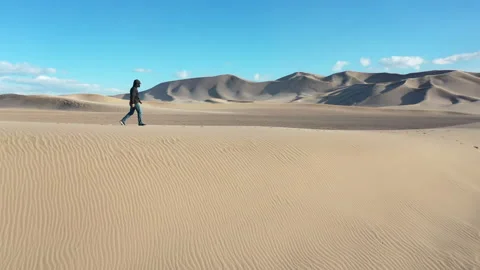 Aerial Drone View of a man walking across the top of a Sand Dune Stock Footage 326723731