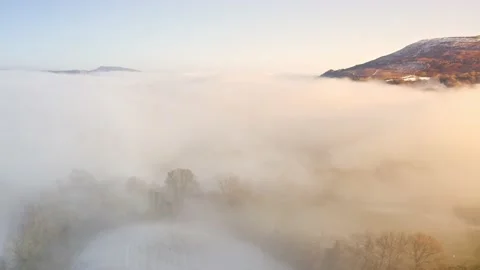 Aerial drone view of mist in a valley on a cold winters day with snow and Stock Footage 239917296