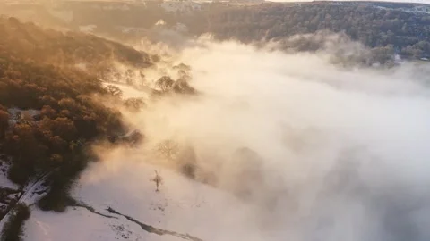 Aerial drone view of mist in a valley on a cold winters day with snow and Stock Footage 240239033