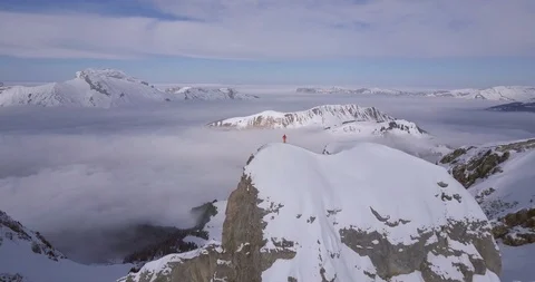 Aerial drone view of a mountain climber skier on the peak summit top of a snow c Stock Footage 91750270