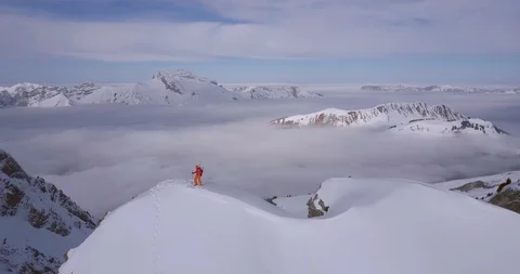 Aerial drone view of a mountain climber skier on the peak summit top of a snow c Stock Footage 91787479