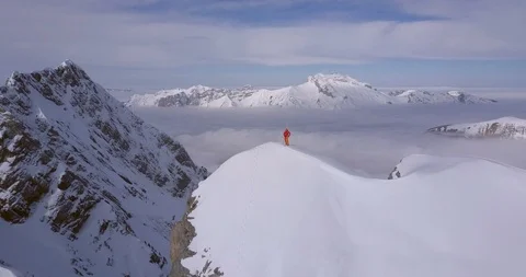 Aerial drone view of a mountain climber skier on the peak summit top of a snow c Stock Footage 96182341