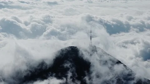 Aerial Drone View of Mountain Peak Rising Above Clouds With Communication Tower Stock Footage 337922036