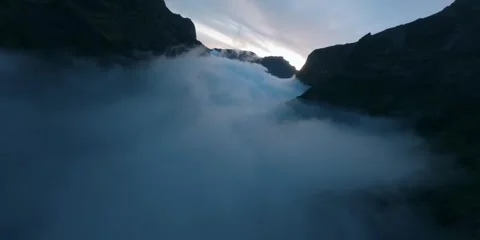Aerial drone view of mountain peaks rising above a thick layer of morning clouds Stockbeeldmateriaal 344086359