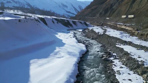 Aerial Drone View of a Mountain River Flowing Through a Snowy Landscape Stock Footage 305396773