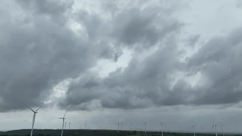 Aerial drone view of multiple wind turbines beneath dark storm clouds. Vídeo Stock 339405329