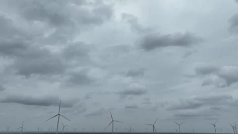Aerial drone view of multiple wind turbines beneath dark storm clouds. Видео 339405338
