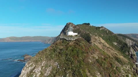 Aerial drone view of Nugget Point lighthouse on coastal cliffs New Zealand Stock Footage 330950045
