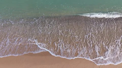 Aerial drone view of ocean waves rolling over sandy beach Stock Footage 320453839