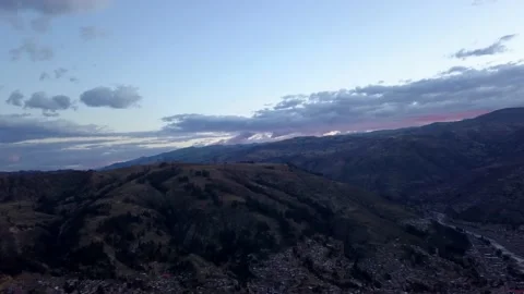 Aerial drone view of an orange sunset on the horizon covered by mountains in the Stock Footage 164588209