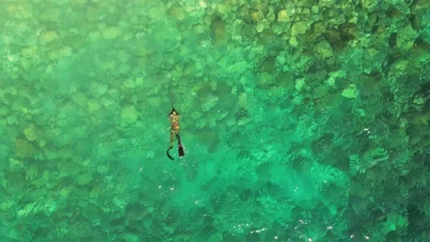 Aerial drone view of a person doing spearfishing on crystal blue water Stock Footage 240113059