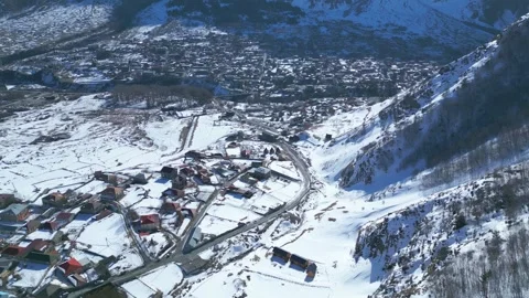 Aerial Drone View of a Remote Mountain Village Surrounded by Snow-Covered Peaks Stock Footage 305396702