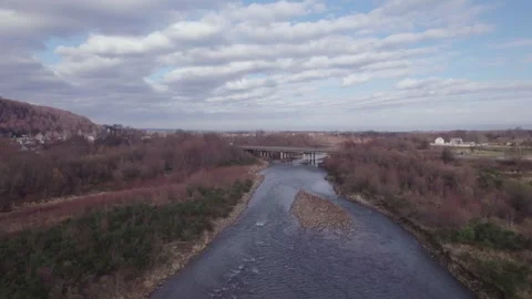Aerial drone view of river with bridge, moving cars and small mountain town Stock Footage 326941171