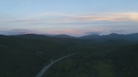 Aerial drone view of road between green hills on sunset. Stock Footage 97209046
