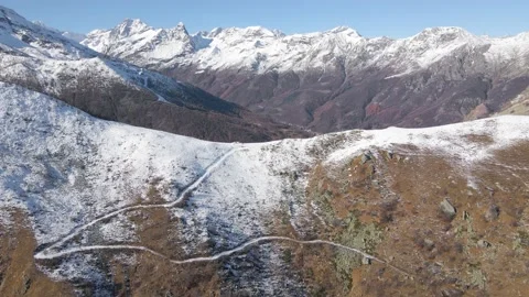 Aerial drone view of road on the top of the snowy mountain and the valley below Stock Footage 215873758