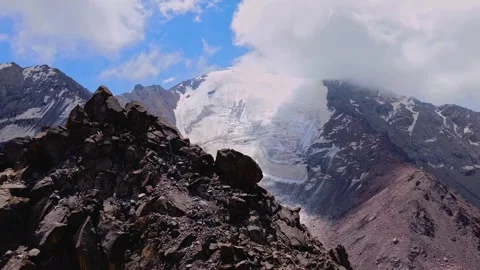 Aerial drone view of rocky ridge overlooking snow capped alpine glacier Stock Footage 345293100