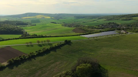 Aerial drone view of rolling green farmland with a solar panel array and a small Stock Footage 336616562