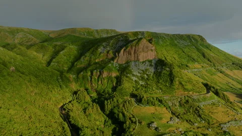 Aerial drone view of a rugged basalt cliff formation rising above the lush green 库存影片 336263221