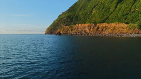 Aerial drone view of a rugged volcanic coastline with steep green mountain Vidéo 335709586