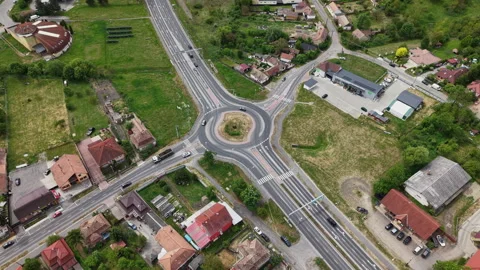 An aerial drone view shows a modern roundabout intersection managing vehicle Stock Footage 335440456
