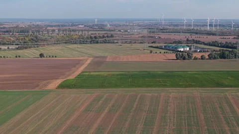 Aerial drone view shows patchwork farmland, biogas facilities and wind turbines Stock Footage 348145783