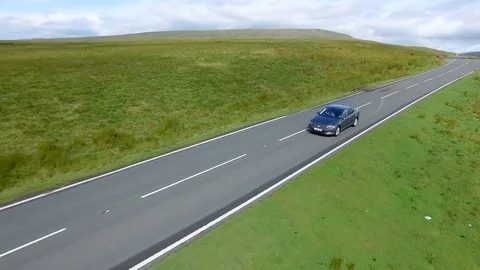 Aerial drone view of a single car driving along an open country road Stock Footage 112387632