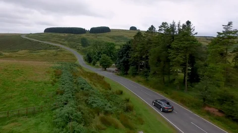 Aerial drone view of a single car traveling down a winding country road Stock Footage 112388097