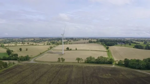 Aerial drone view of a single wind turbine turning surrounded by fields Stock Footage 158952738