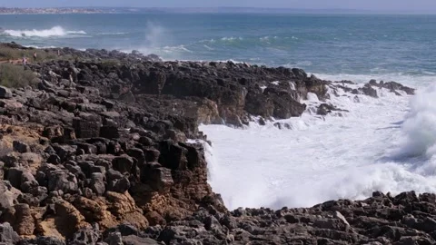 Aerial drone view of slow motion waves crashing against rocky shoreline at Stock Footage 288457624